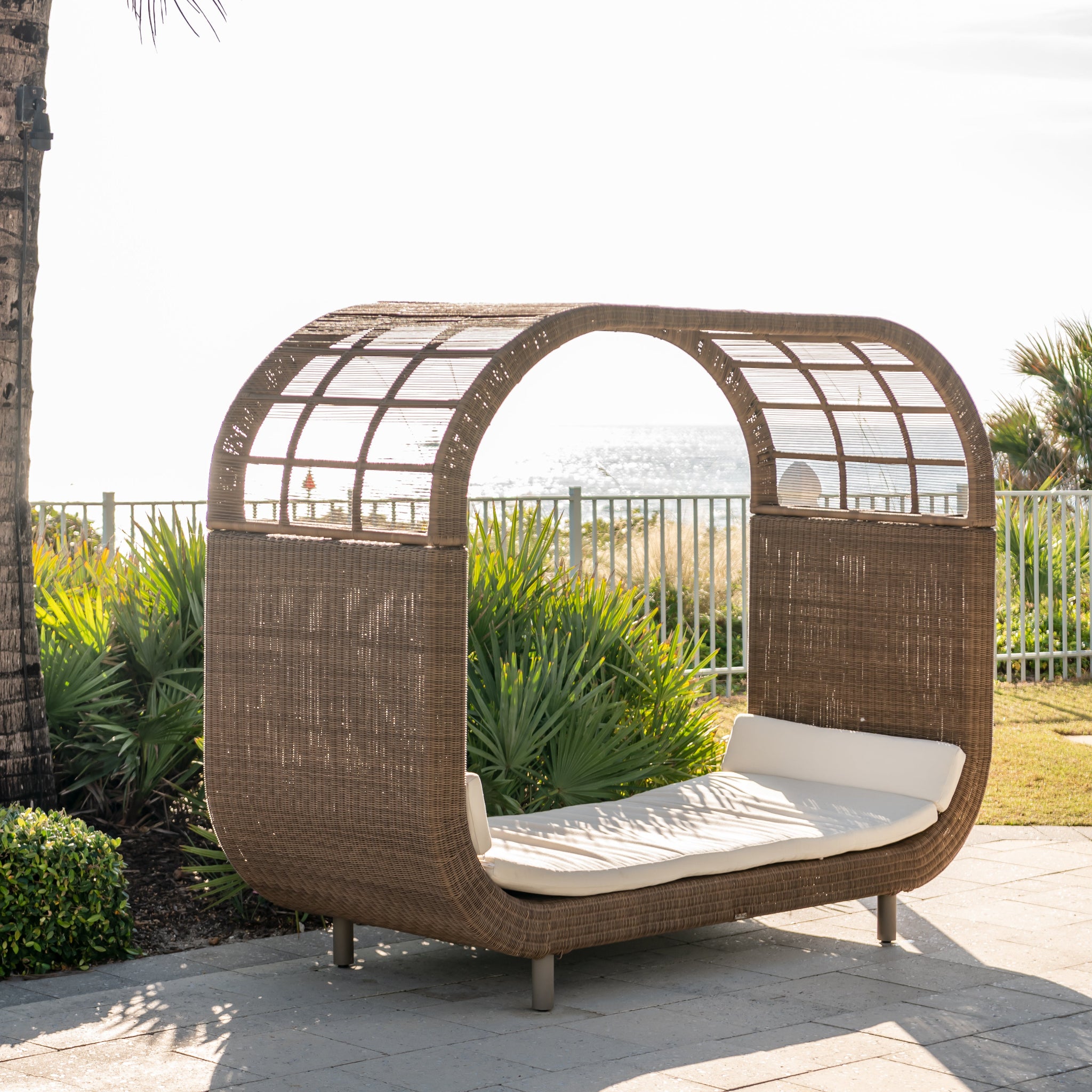 Wicker outdoor daybed with canopy in a garden setting